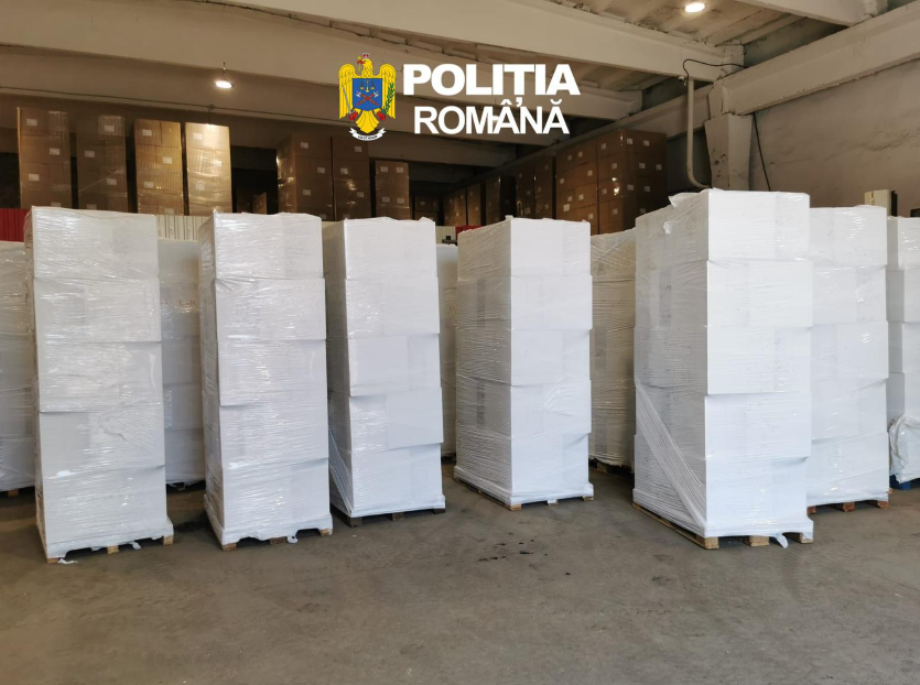 Stacks of white-wrapped pallets in a spacious warehouse with the Poliția Română logo overhead