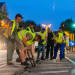 Group of construction workers in reflective vests repairing a street at night.