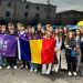 Group of students posing in front of a bus, holding a purple 'Cyber Moon' banner and a Romanian flag.