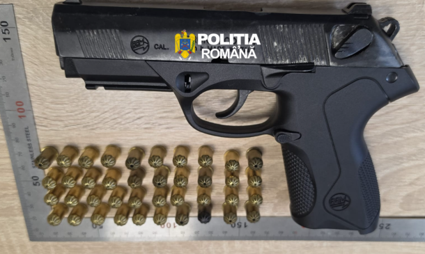 Black semi-automatic pistol with Romanian Police branding, placed on a wooden surface, with multiple brass cartridges arranged in rows below and a metal ruler for scale.