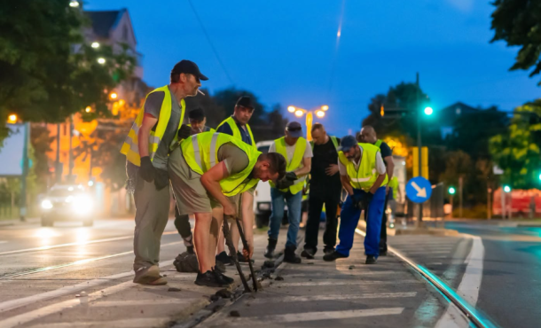 Group of construction workers in reflective vests repairing a street at night.