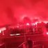 Crowd at night waving red flares, smoke lighting the scene in an intense red glow
